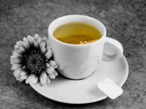 black and white backround with flower and tea-cup and into green tea in color