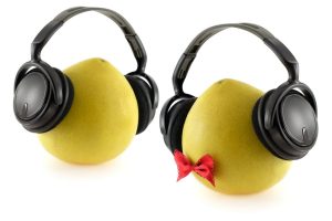 Two pomelo fruits with headphones over white background